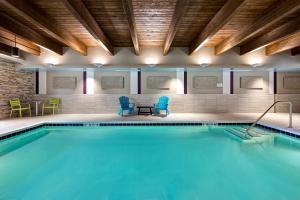 林肯郡Home2 Suites By Hilton Lincolnshire Chicago的一个带蓝色椅子和桌椅的游泳池