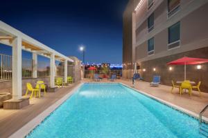 埃文代尔Home2 Suites By Hilton Phoenix Avondale, Az的一座带桌椅的游泳池以及一座建筑