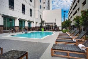 休斯顿Home2 Suites by Hilton Houston Medical Center, TX的一座带椅子的建筑中的游泳池以及一座游泳池