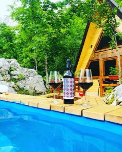 ŠavnikEtno apartmani Komarnica的游泳池畔的桌子上放两杯葡萄酒