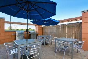 本顿维尔Home2 Suites By Hilton Bentonville Rogers的庭院里配有两张桌子和椅子以及遮阳伞