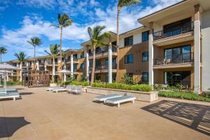 基黑Hilton Grand Vacations Club Maui Bay Villas的一座带长椅和棕榈树的大型公寓大楼