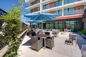 森尼维耳市Hampton Inn & Suites Sunnyvale-Silicon Valley, Ca的一个带桌椅和遮阳伞的庭院
