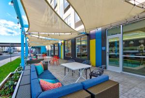 阿什本Tru By Hilton Ashburn One Loudoun, Va的庭院设有蓝色的沙发和桌椅