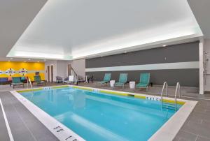 阿什本Tru By Hilton Ashburn One Loudoun, Va的游泳池位于酒店房间,周围设有椅子