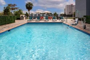 迈阿密Home2 Suites By Hilton Miami Airport South Blue Lagoon的大楼内带椅子的大型游泳池