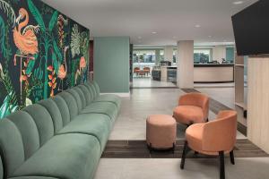 迈阿密Home2 Suites By Hilton Miami Airport South Blue Lagoon的客厅配有绿色沙发和两把椅子