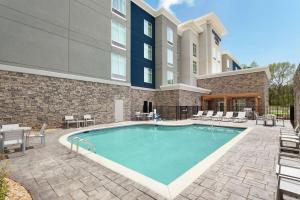 麦克多诺Homewood Suites By Hilton Mcdonough的一座带椅子的游泳池以及一座建筑