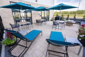 HuntleyHampton Inn By Hilton Huntley Chicago的一个带蓝色桌椅和遮阳伞的庭院