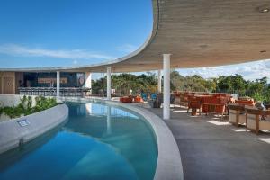 坎昆Hilton Garden Inn Cancun Airport的一座带桌椅的游泳池位于酒店大楼旁