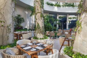 坎昆Hilton Garden Inn Cancun Airport的一间设有桌椅和树木的餐厅