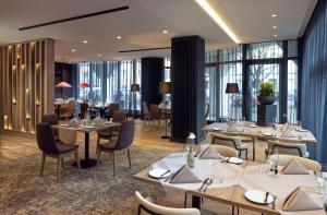 汉诺威DoubleTree by Hilton Hannover Schweizerhof的餐厅设有桌椅和窗户。