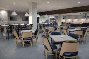 博林格林Embassy Suites By Hilton Bowling Green的一间带桌椅的餐厅和一间酒吧