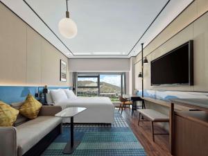 拉萨拉萨天峰希尔顿花园酒店的酒店客房配有床、沙发和电视。