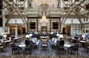 华盛顿Waldorf Astoria Washington DC的大堂设有吊灯和桌椅