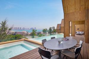 多哈Katara Hills Doha, Lxr Hotels & Resorts的游泳池旁带桌椅的天井