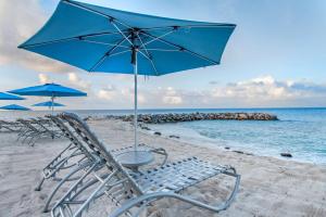 辛普森湾Hilton Vacation Club Flamingo Beach Sint Maarten的海滩上的两把椅子和一把遮阳伞