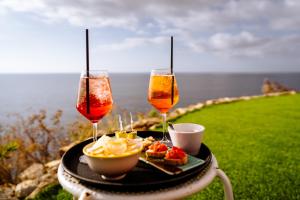 康培斯Resort Faro di Punta Fenaio的一张桌子,上面放着两杯酒和一盘食物