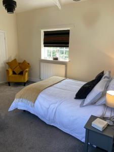CheswardineSTABLE COTTAGE的卧室配有白色的床和黄色椅子
