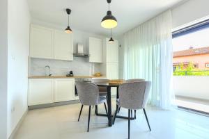 罗维尼Apartments La Scogliera Rovinj的厨房配有白色橱柜和桌椅