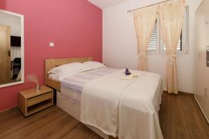 马卡尔斯卡Blue home的卧室配有白色的床和粉红色的墙壁