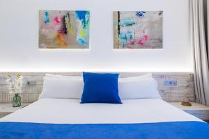 科拉雷侯Hotel Vacanzy Urban Boutique Adults Only的一间卧室配有一张蓝色和白色的床,并装饰有两幅画作