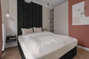 格利维采APARTIO ROOMS Gliwice的一间卧室配有一张白色的床和黑色床头板