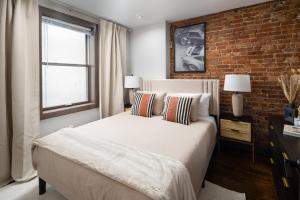 纽约Modern Luxury 3BD and 2BA in the Heart of East Village的一间卧室设有一张床和砖墙