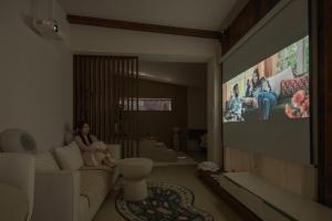 全州市Jeonju Hanok Village, Maison14的坐在客厅的沙发上的女人,客厅里配有电视