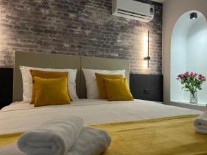 普拉Arena Prestige Rooms的一间卧室配有一张带黄色枕头的床和砖墙
