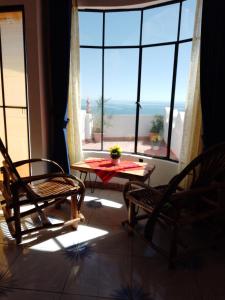 科帕卡巴纳Jardín Andino hostal的客房设有桌椅和大窗户。