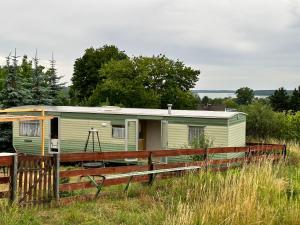 哈日科维Domek za świerkami的绿色大篷车,位于带围栏的田野