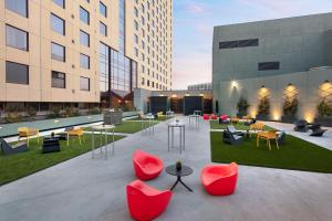 奥克兰奥克兰市中心万豪酒店的庭院设有红色的桌椅和建筑