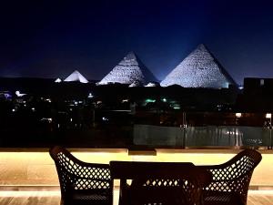 开罗Celia Pyramids View inn的夜间在大楼顶部的桌椅