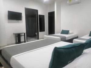 库库塔Aveiro Hotel的客房设有三张床和一台平面电视。