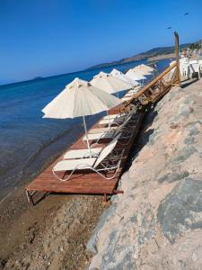 塞费里希萨尔Apelles Butik Otel的海滩上一排带遮阳伞的躺椅