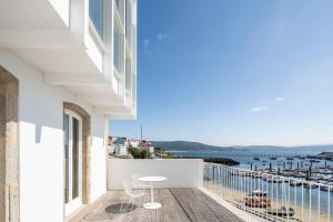 菲尼斯特雷Porto Real Hotel的阳台配有桌椅,享有海景。