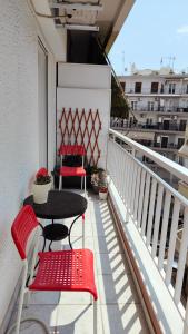 塞萨洛尼基Think Home, exploring the center of Thessaloniki的阳台配有2把红色椅子和桌子
