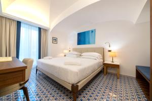 伊斯基亚OraBlu Exclusive Villas的酒店客房配有一张床、一张书桌和一张书桌。