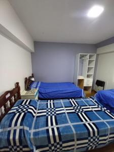 乌斯怀亚hostel comunidad Ushuaia的一间卧室配有两张带蓝色棉被的床