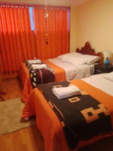 奥兰太坦波hostal ollantaytambo apartments的酒店客房带两张带橙色床单的床