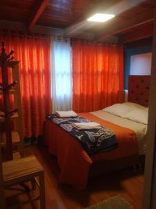 奥兰太坦波hostal ollantaytambo apartments的一间卧室配有两张床和橙色窗帘