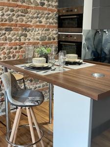 图卢兹Appartement climatisé avec balcon et parking privé的厨房配有带盘子和玻璃杯的木桌