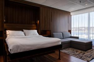 萨格奈希库蒂米酒店的一间卧室配有一张床、一张沙发和一个窗口