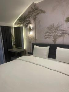 特拉布宗Uzunkum Hotel的卧室配有一张白色大床,墙上挂着棕榈树