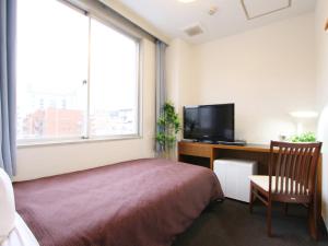 东京HOTEL LiVEMAX BUDGET Tokyo Kiba的一间卧室配有一张床和一张书桌及电视
