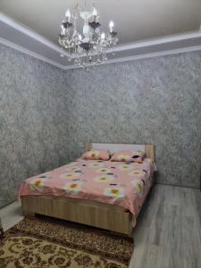 奇姆肯特Deluxe的一间卧室配有粉红色的床和吊灯。