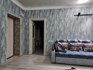 奇姆肯特Deluxe的一间配有沙发和蓝色壁纸墙的房间