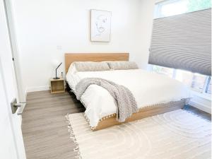 彭蒂克顿*NEW* HAVN HOUSE MODERN RETREAT - STEPS FROM BEACH的一间卧室配有一张带白色床单的床和一扇窗户。