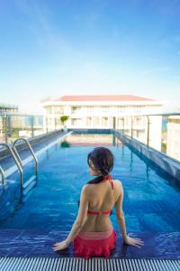 岘港Sea Wind Hotel by THG的坐在游泳池里的比基尼女人